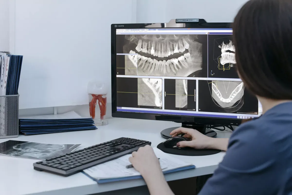 Persona mirando una pantalla con imágenes de radiografías de una boca